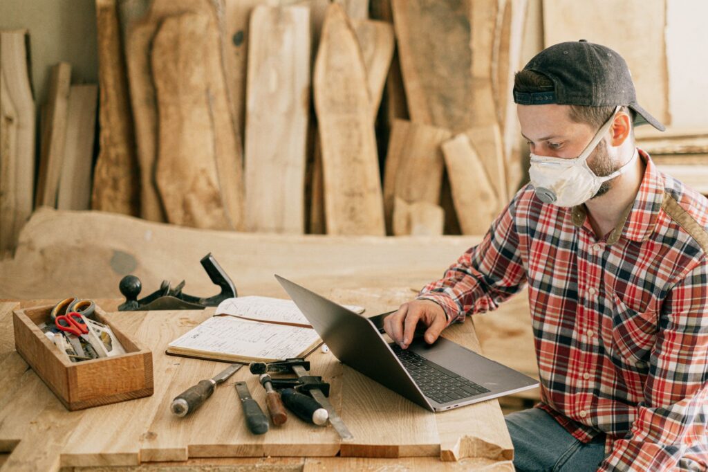 man using a laptop at a wood workshop