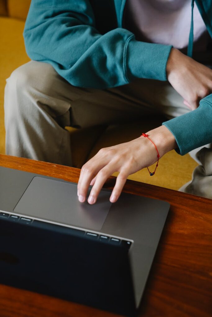 crop freelancer working on laptop on sofa at home