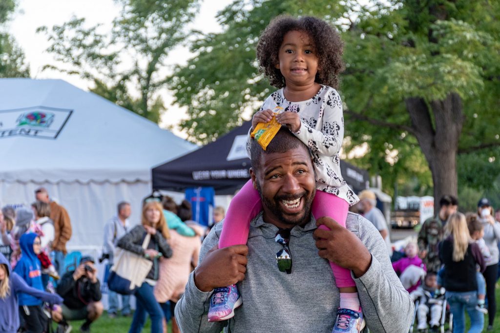 girl sitting on smiling man s shoulder