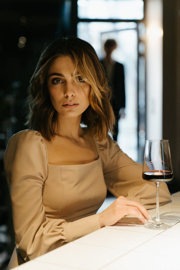 woman in brown long sleeve shirt holding wine glass