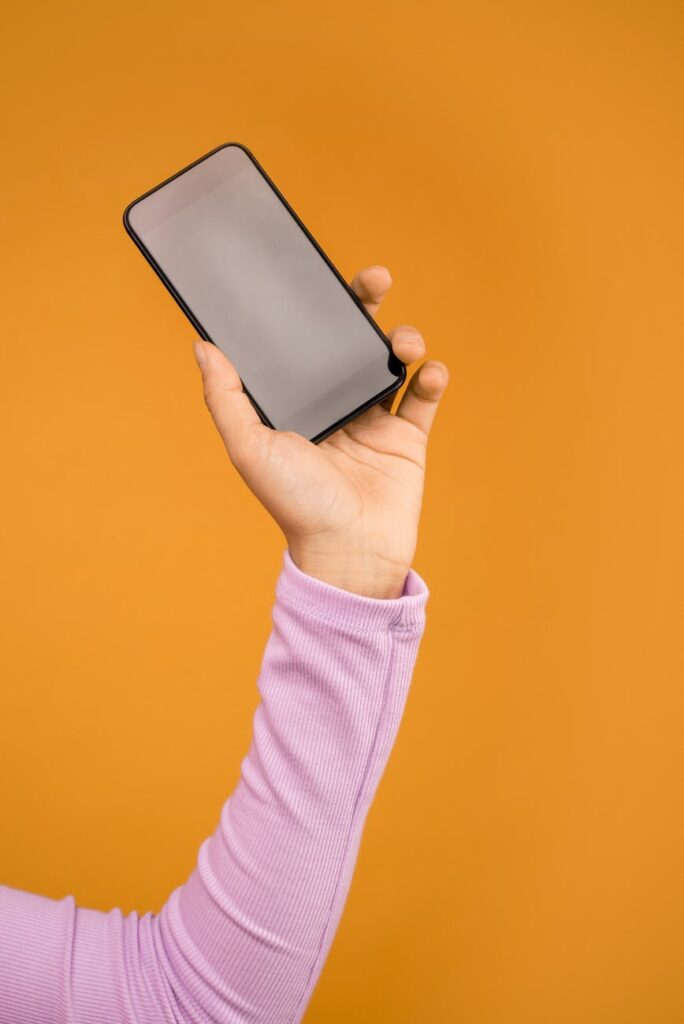 person holding black smartphone in orange background