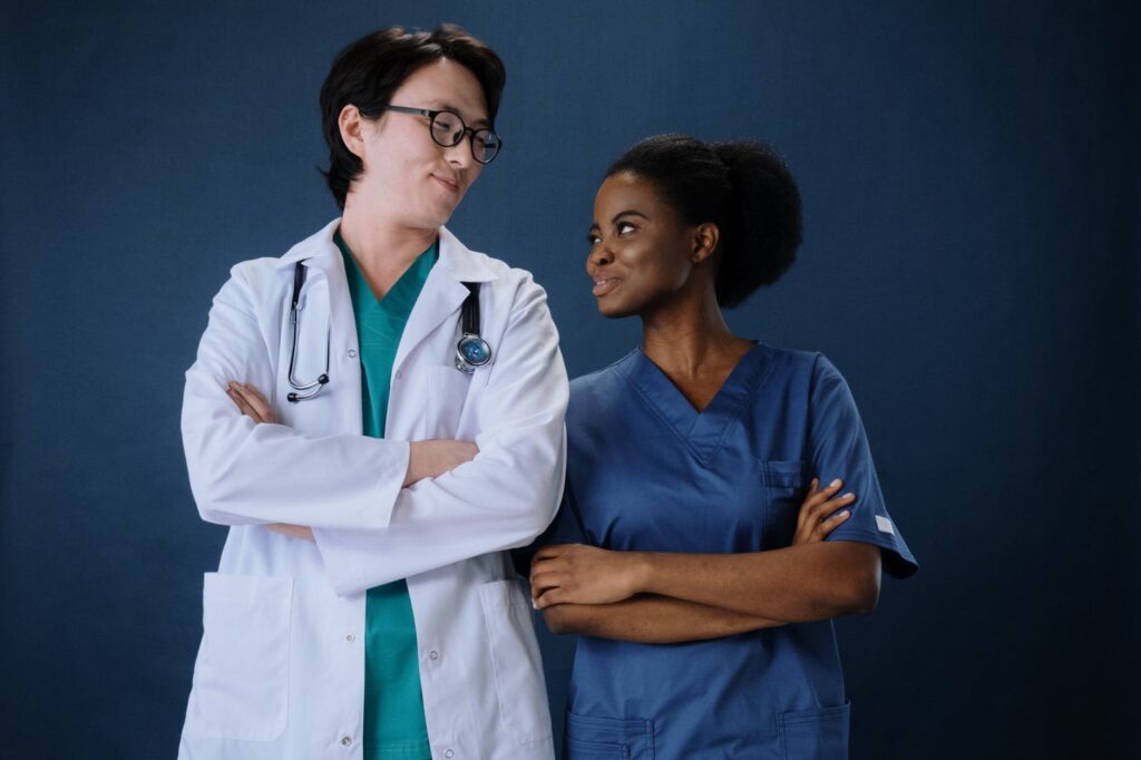 woman in blue scrub suit standing beside a man in white laboratory gown