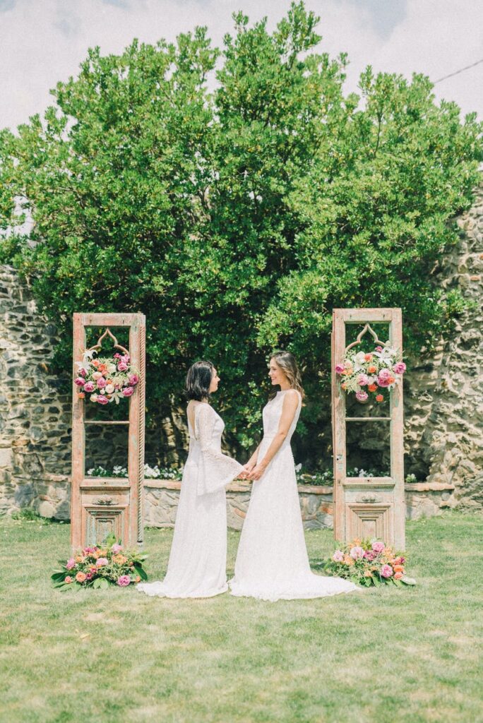 photo of woman in wedding dress standing while holding hands