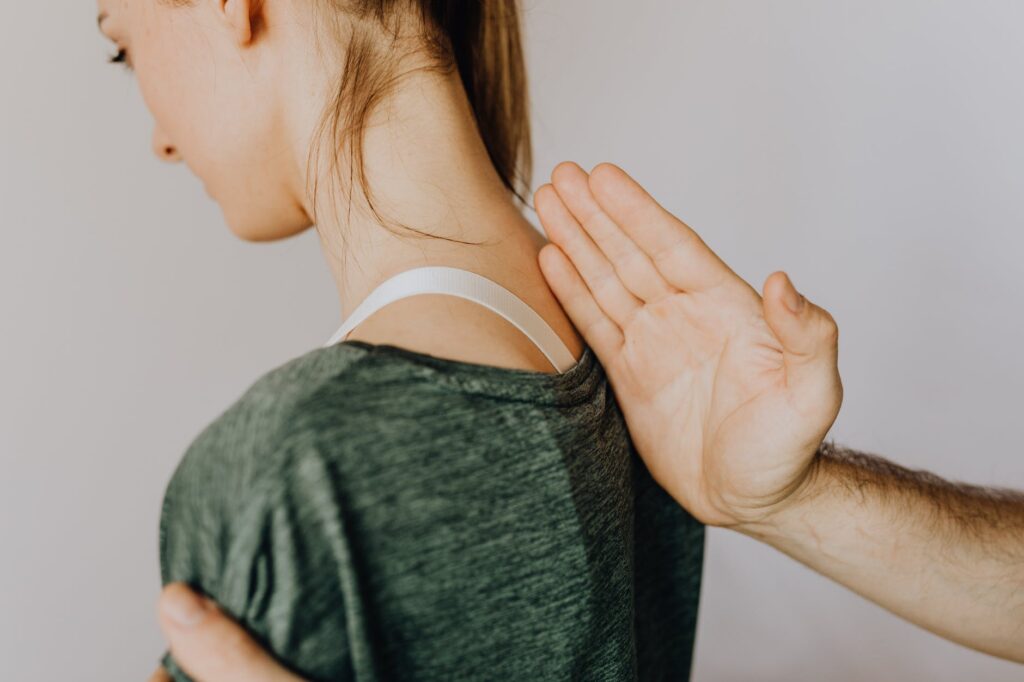 crop unrecognizable orthopedist checking up back of woman in clinic