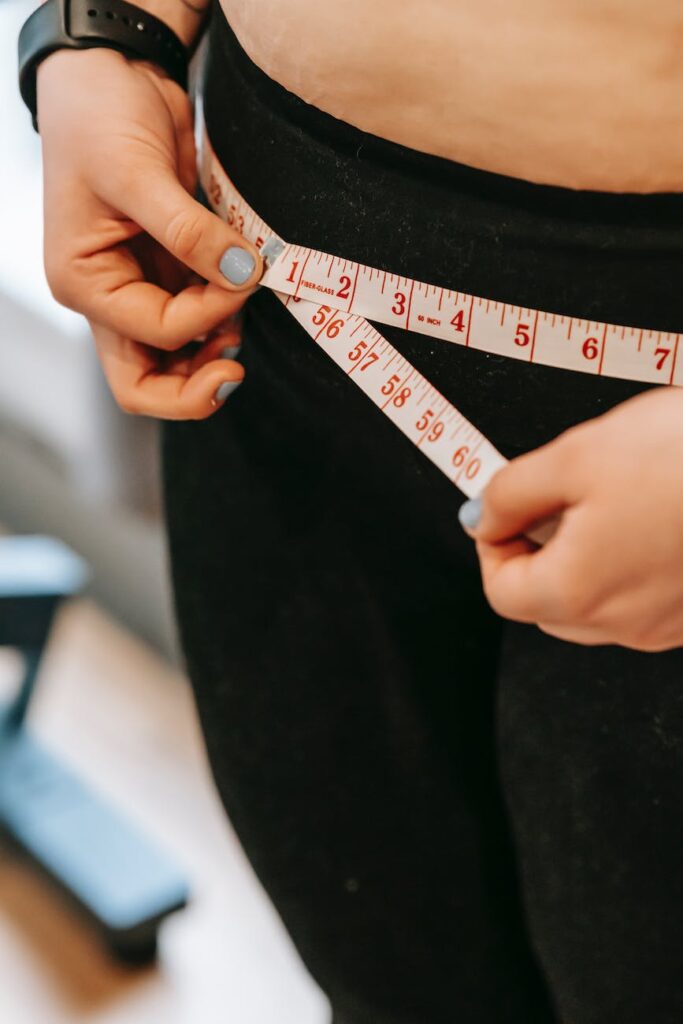 plus size woman measuring hips in gym